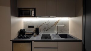 A compact kitchen with a built-in microwave, a coffee machine, and a sink.