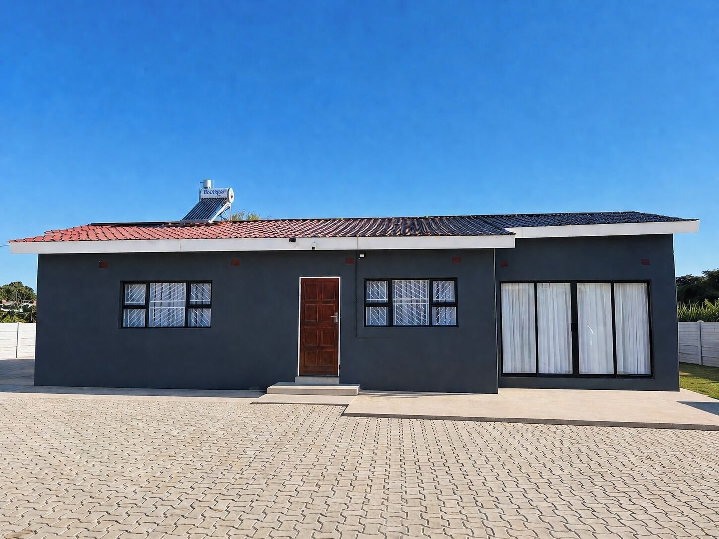 Ein modernes, zweistöckiges Gebäude mit roten Ziegeln auf dem Dach, einem zentralen Eingang und einer Garage mit weißen Vorhängen.