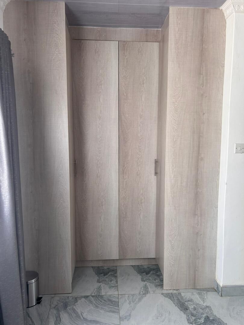 Ein Zimmer mit Schrank, Mülleimer und Fliesenboden.