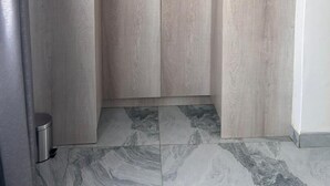 Una habitación con armario, cubo de basura y piso de baldosas.