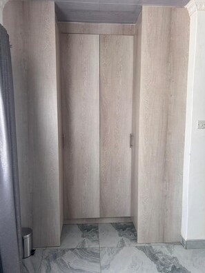 Una habitación con armario, cubo de basura y piso de baldosas.