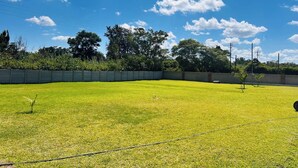Un campo de césped cuidado con cielo despejado y árboles al fondo.