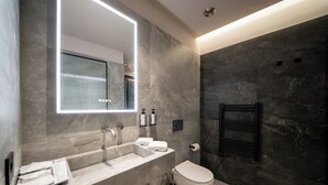 A modern bathroom with a large mirror, a sink, a toilet, and a towel rack.
