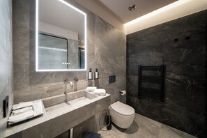 A modern bathroom with a large mirror, a sink, a toilet, and a towel rack.