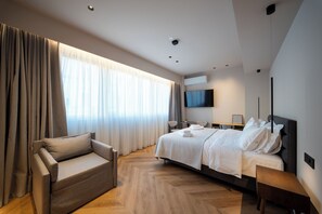 Une chambre d’hôtel moderne équipée d’un lit, d’un canapé, d’une télévision et d’une grande fenêtre avec des rideaux.