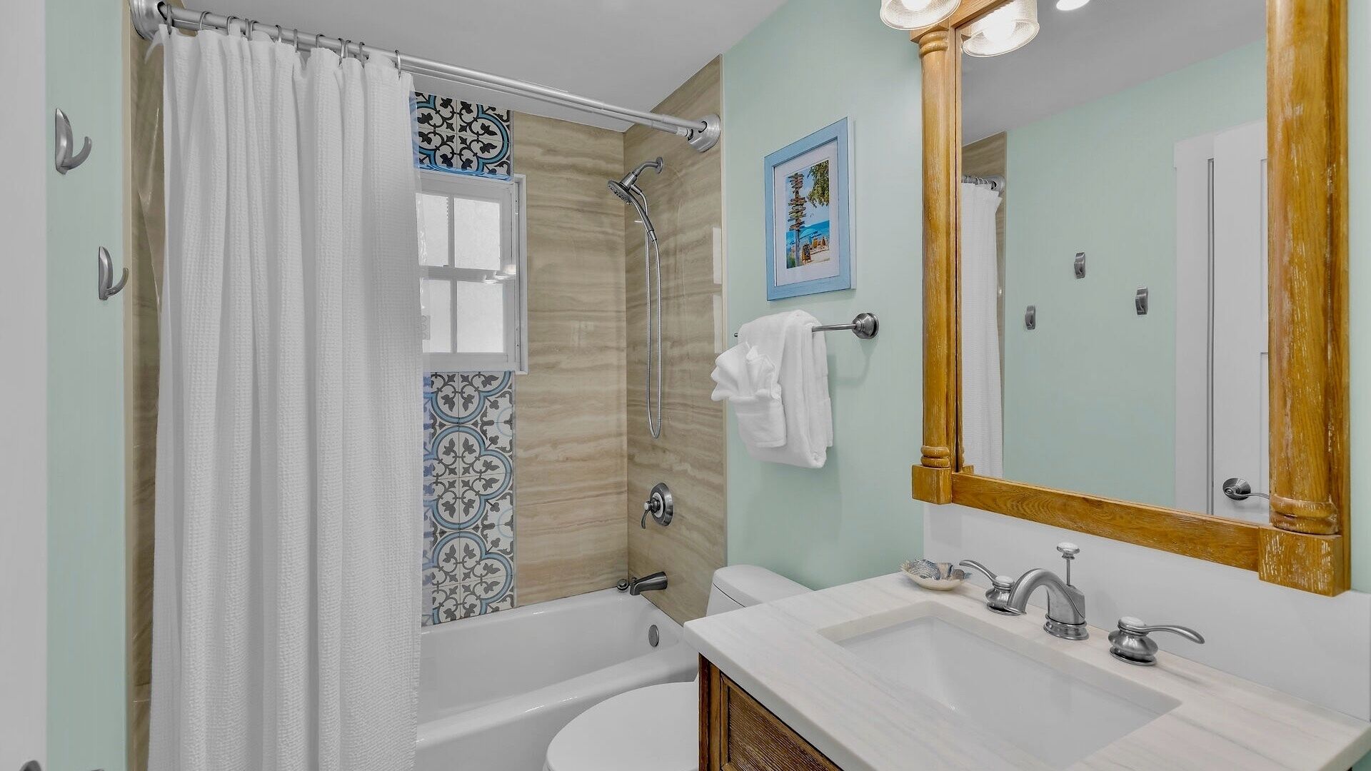 A bathroom with a bathtub, shower, sink, and a mirror.