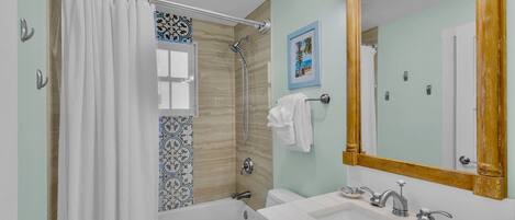 A bathroom with a bathtub, shower, sink, and a mirror.