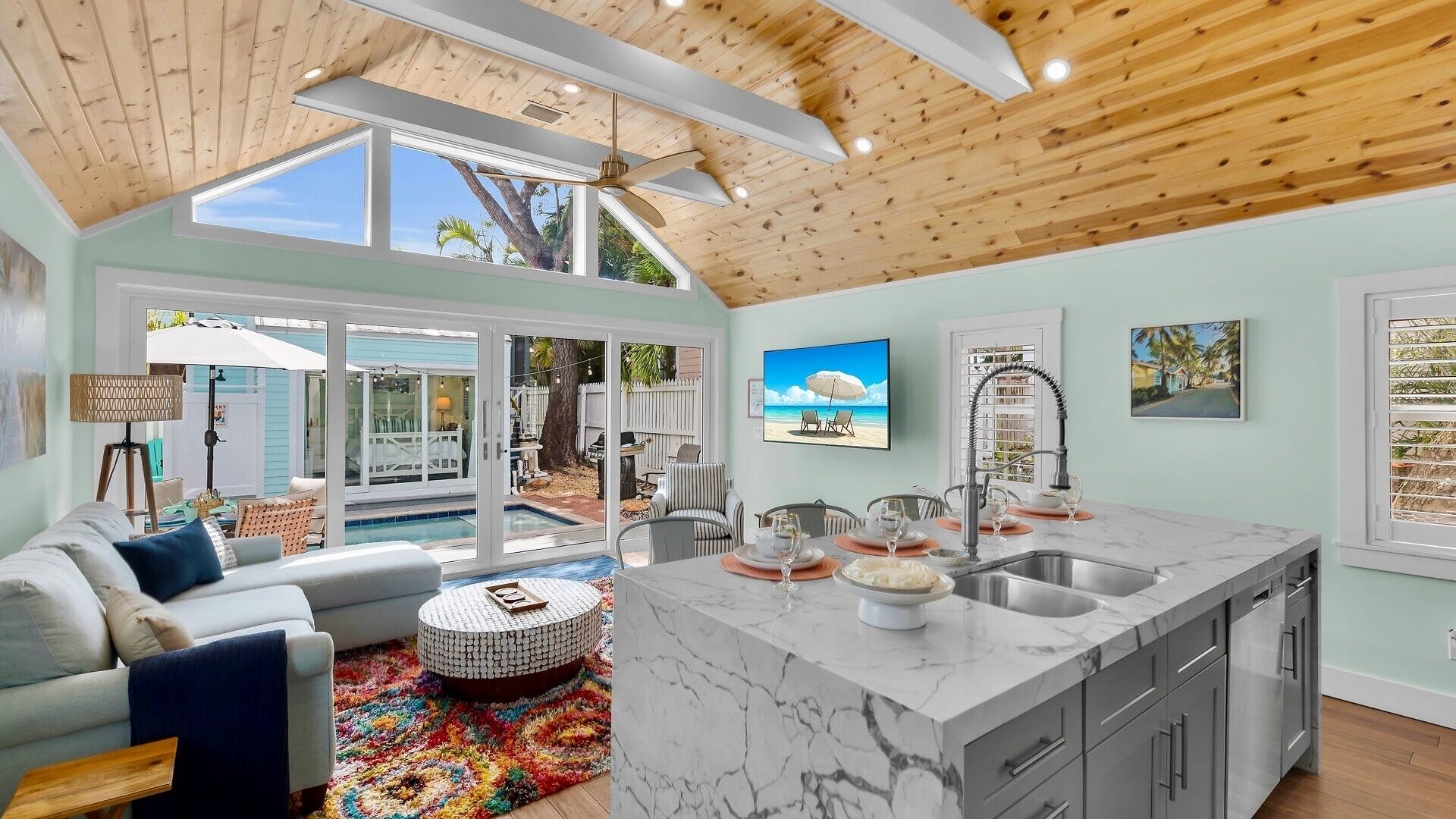 A spacious living area with a large window, a dining table set for two, and a kitchen with a marble island.