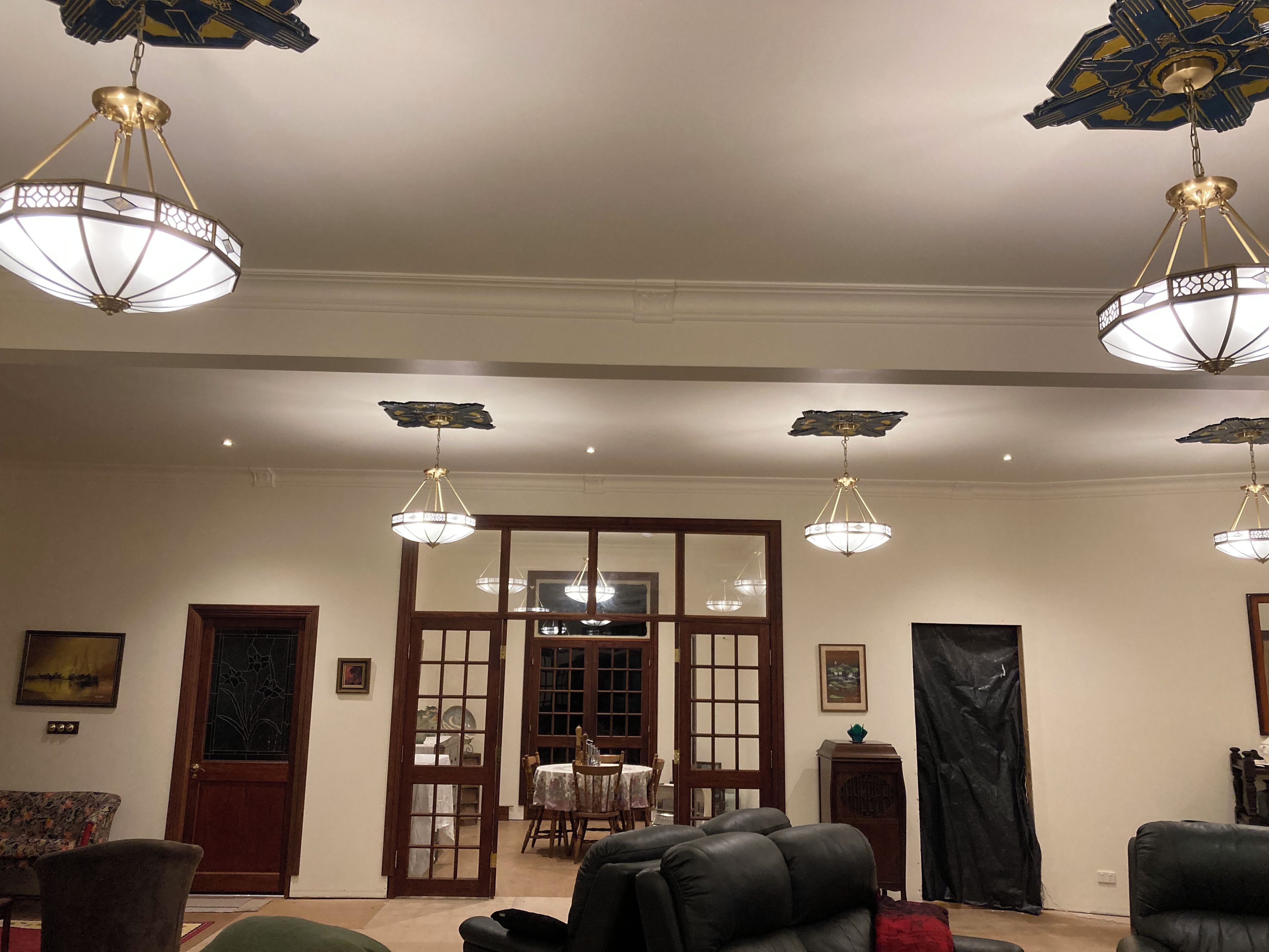 Ein Zimmer mit mehreren Pendelleuchten, einer Holztür, einem Esstisch mit Stühlen und einem Sofa.