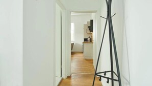 Un pasillo con un perchero, una puerta que da a una cocina y una escalera.