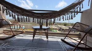Una silla hamaca, una mesa y vistas a una piscina y edificios.