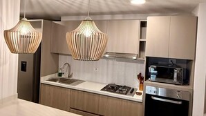 Una cocina moderna con lámparas colgantes, microondas y estufa.