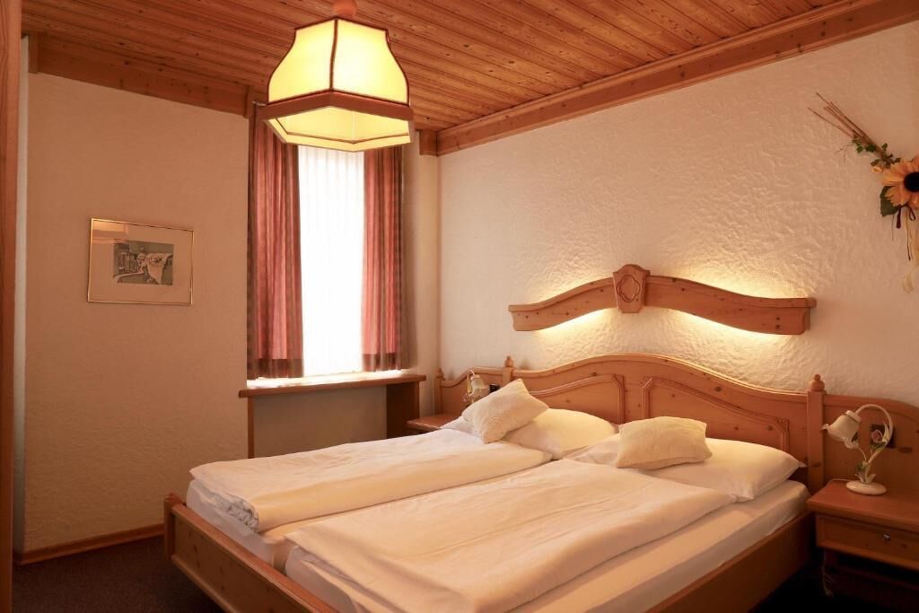 A double bed with a wooden headboard, a bedside table, and a hanging lamp.