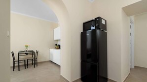 Una cocina compacta con un refrigerador negro, una mesa de comedor con sillas y un mueble pequeño.
