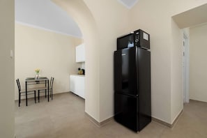 Una cocina compacta con un refrigerador negro, una mesa de comedor con sillas y un mueble pequeño.