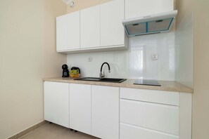 A kitchen with white cabinets, a black faucet, and a built-in range hood. - Stylish Apartment in Bielsko-Biala | Near the Town Hall (Bielsko-Biała)