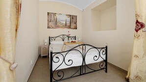 A bedroom with a bed, a bedside table, a lamp, a painting on the wall, and a window. - Practical Studio for a Business Stay | Close to the City Centre (Bielsko-Biała)