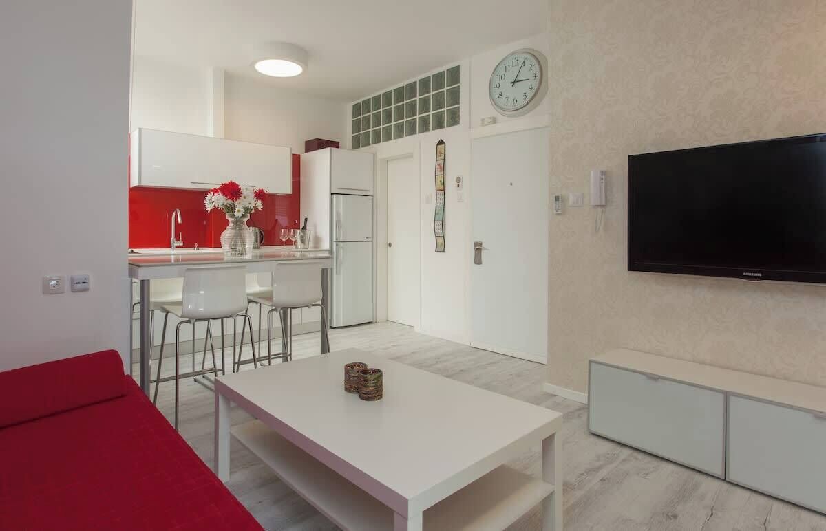 Un espacio habitable compacto con kitchenette, comedor y televisor.