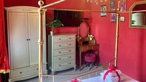 Ein Schlafzimmer mit einem Himmelbett, einem Schminktisch, einer Kommode und einer Chandelier.