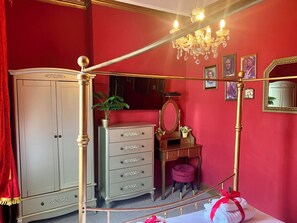 A bedroom with a four-poster bed, a dresser, a vanity with a mirror, and a chandelier. - Downton I (Alnwick)