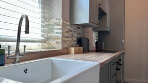 Eine moderne Küche mit integriertem Spülbecken, einer Stein-Spritzschutzwand und Edelstahl-Schränken.
