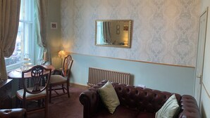 Ein Zimmer mit Esstisch, Stühlen, einer Couch, einem Heizkörper und einer Chandelier.