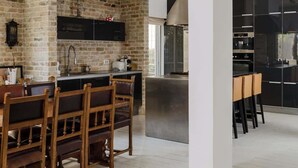 Une cuisine moderne avec un mur en briques, une table à manger en bois et des meubles de rangement noirs.