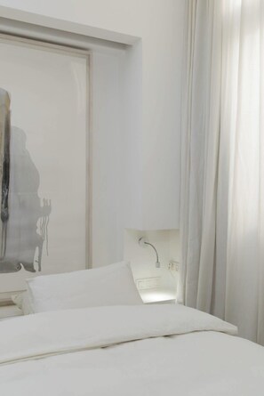 A bedroom with a bed, a nightstand, and a wall-mounted light fixture. - Gold Gordon Beach Apartments - Chefs apartment (Tel Aviv-Yafo)