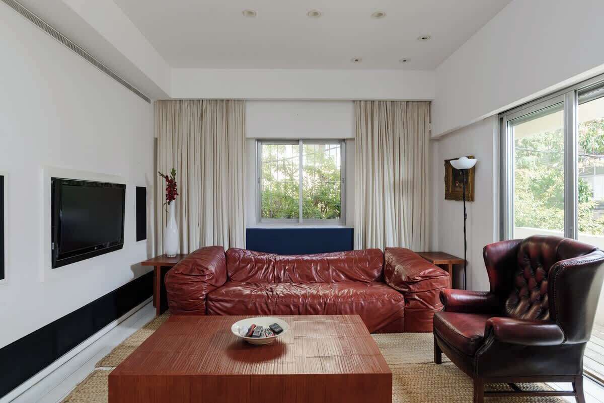 Ein modernes Wohnzimmer mit einer Ledersofa, einem Couchtisch und einem Fernseher.