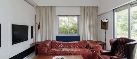 A modern living room with a leather sofa, a coffee table, and a television.
