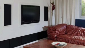 Un salon moderne avec un téléviseur à écran plat fixé au mur, un canapé en cuir et une table basse en bois.