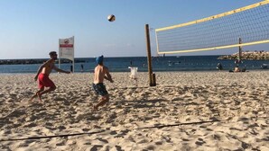 Een strandvolleybalwedstrijd met een net en spelers op de voorgrond.