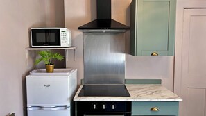 Une cuisine de taille réduite équipée d’un four à micro-ondes, d’une cuisinière et d’un évier.