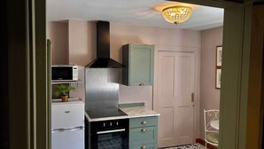 A compact kitchen with a microwave, stove, and a built-in oven. - Downton II (Alnwick)