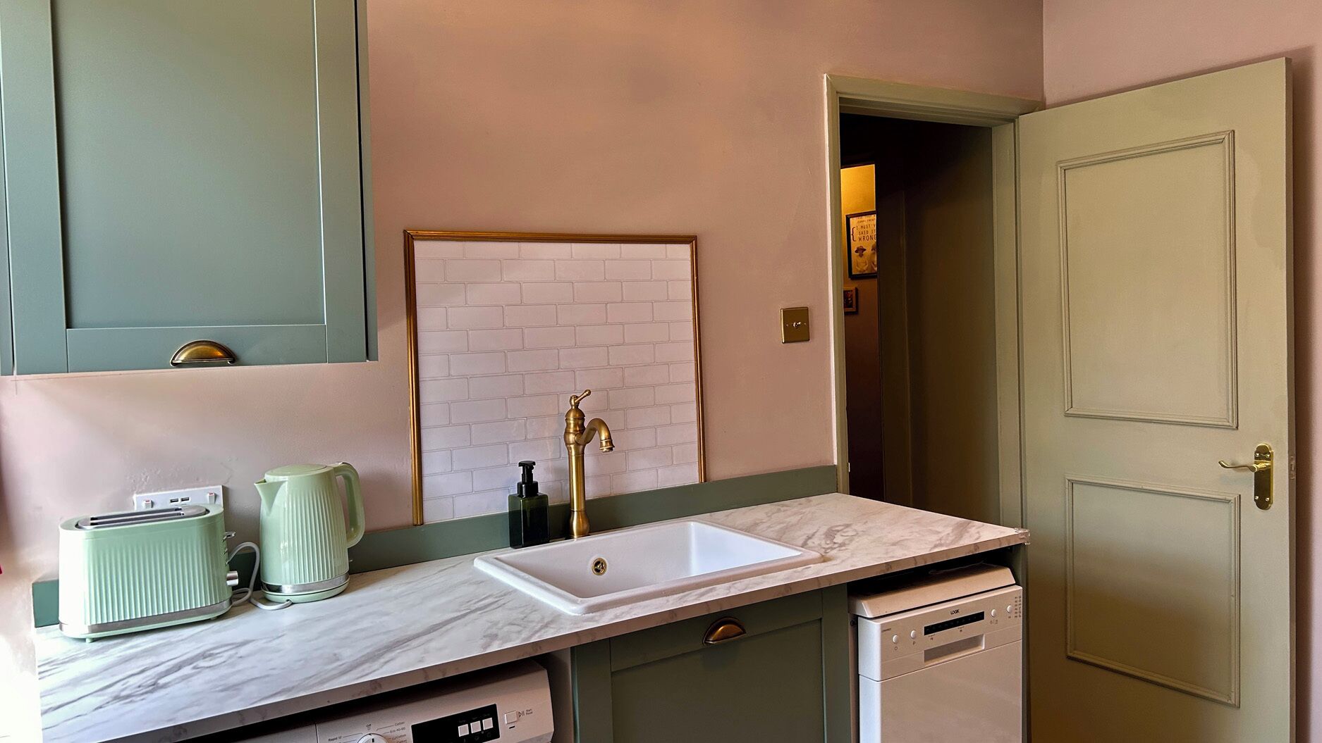 A kitchen with a white sink, a green countertop, and a white dishwasher.