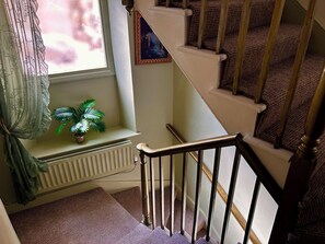 A staircase with a handrail, a window with a plant, and a picture frame on the wall. - Downton II (Alnwick)