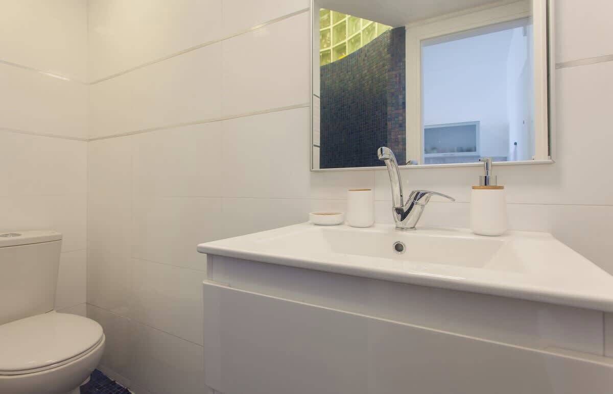 A modern bathroom with a white sink, mirror, and toilet.