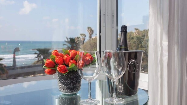 A table with a vase of red tulips, two wine glasses, and a champagne bottle.