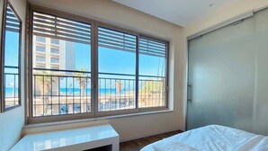 Ein Schlafzimmer mit großem Fenster, einem Bett, einer Sitzbank und einer Schiebetür.