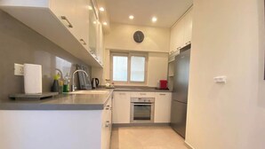 Eine moderne Küche mit weißen Schränken, einem Backofen und einem Edelstahl-Kühlschrank.