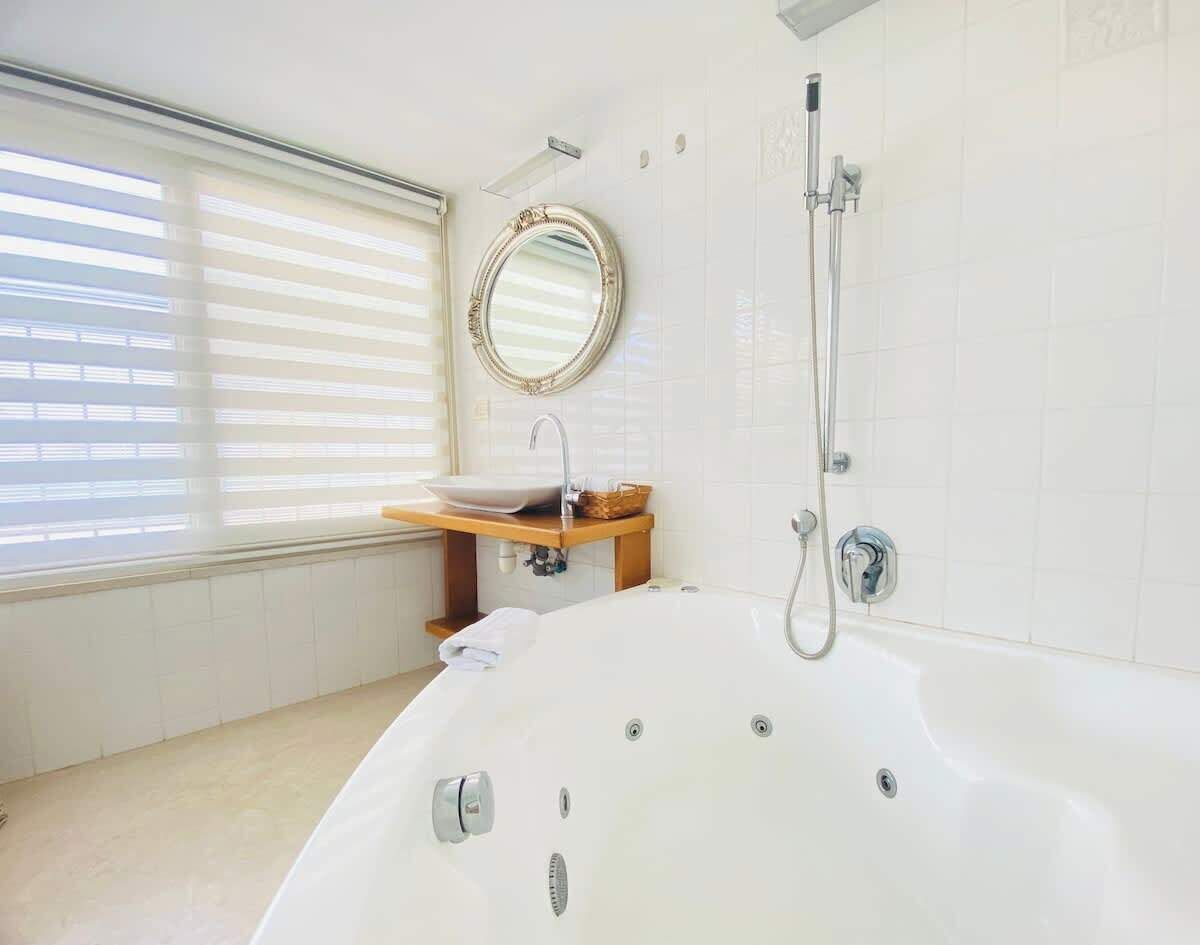 A modern bathroom with a freestanding bathtub, a round mirror, a sink with a vessel basin, and a showerhead.