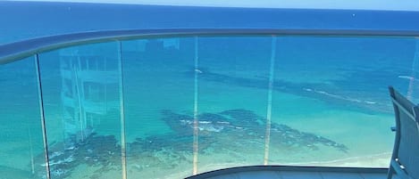 A balcony with a clear view of the ocean and a sandy beach.
