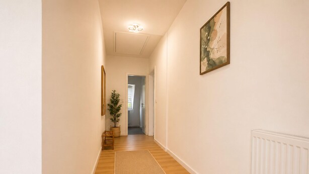 A hallway with a wooden floor, a rug, a plant, and a framed picture on the wall. - Zum Rheinberg - Marksburg Panorama (Braubach)