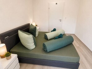 A neatly made bed with pillows and rolled towels, a bedside lamp, and a small plant on a bedside table. - Zum Rheinberg - Marksburg Panorama (Braubach)