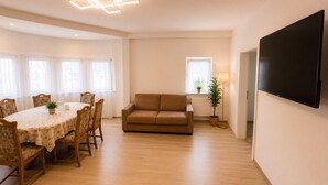 Una sala de estar moderna con una mesa de comedor, un sofá y un televisor de pantalla plana.