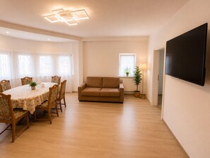 Ein modernes Wohnzimmer mit Esstisch, Sofa und Flachbildfernseher.
