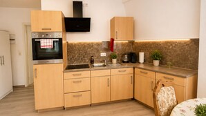 Una cocina moderna con armarios de madera, horno empotrado, cafetera y un lavamanos pequeño.