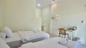 Habitación de hotel con dos camas, un escritorio, una silla, un espejo y una mesita con una tetera y tazas.