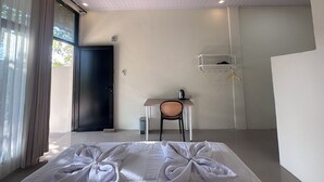 Een hotelkamer met een bed, bureau, stoel, kapstok en raam met gordijnen.