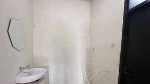 Een badkamer met een witte wastafel, een spiegel en een metalen droogrek.